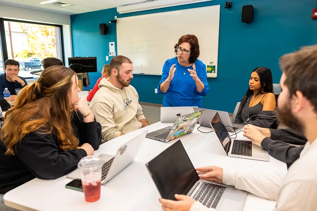 classroom with teacher and students and laptops